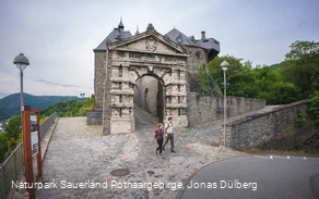 Zwei Wanderer am Burgtor der Burg Altena am Startpunkt vom Sauerland-Höhenflug